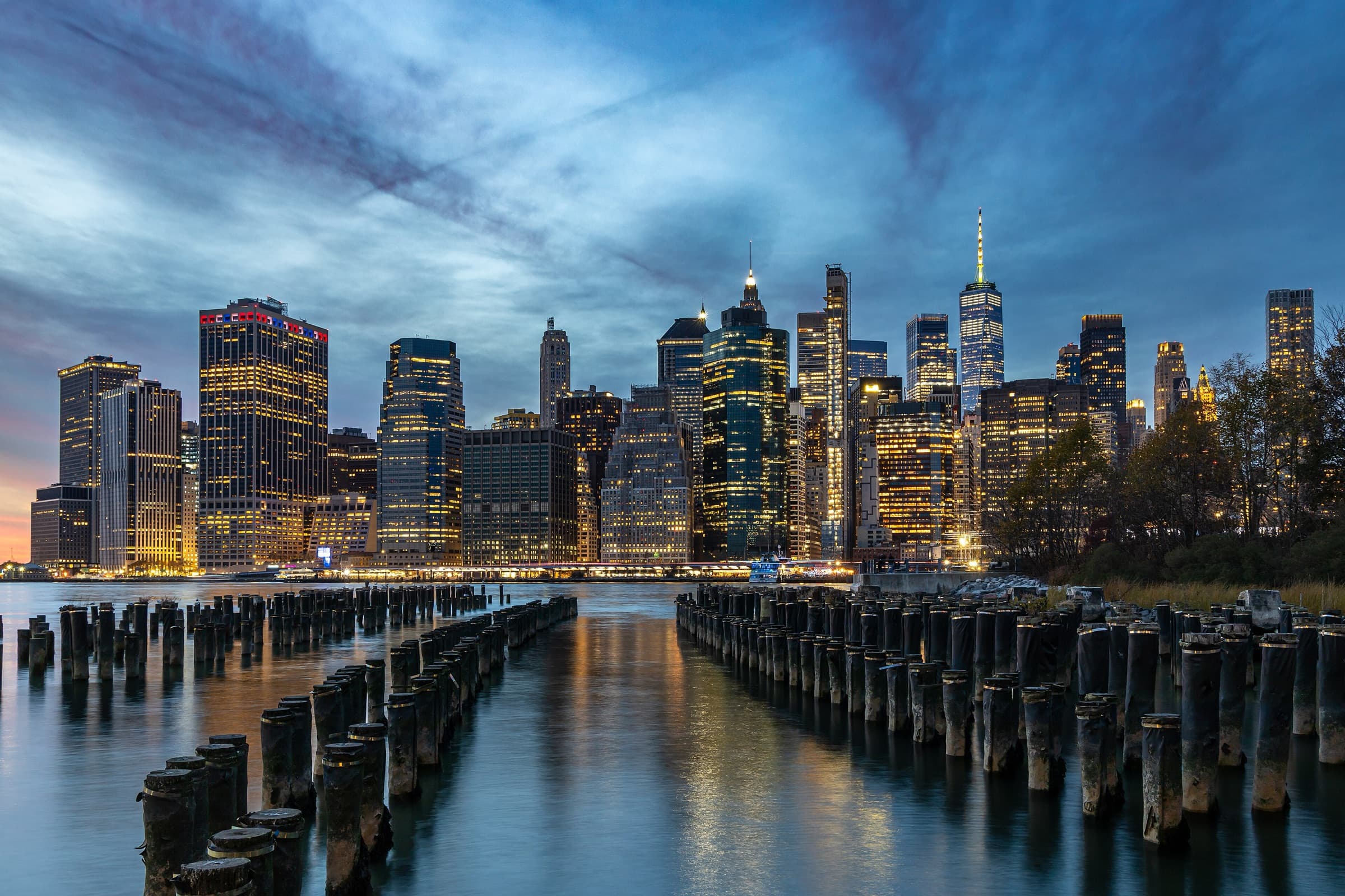 Lower Manhattan’s skyline at dusk behind the remains of old pier pilings
