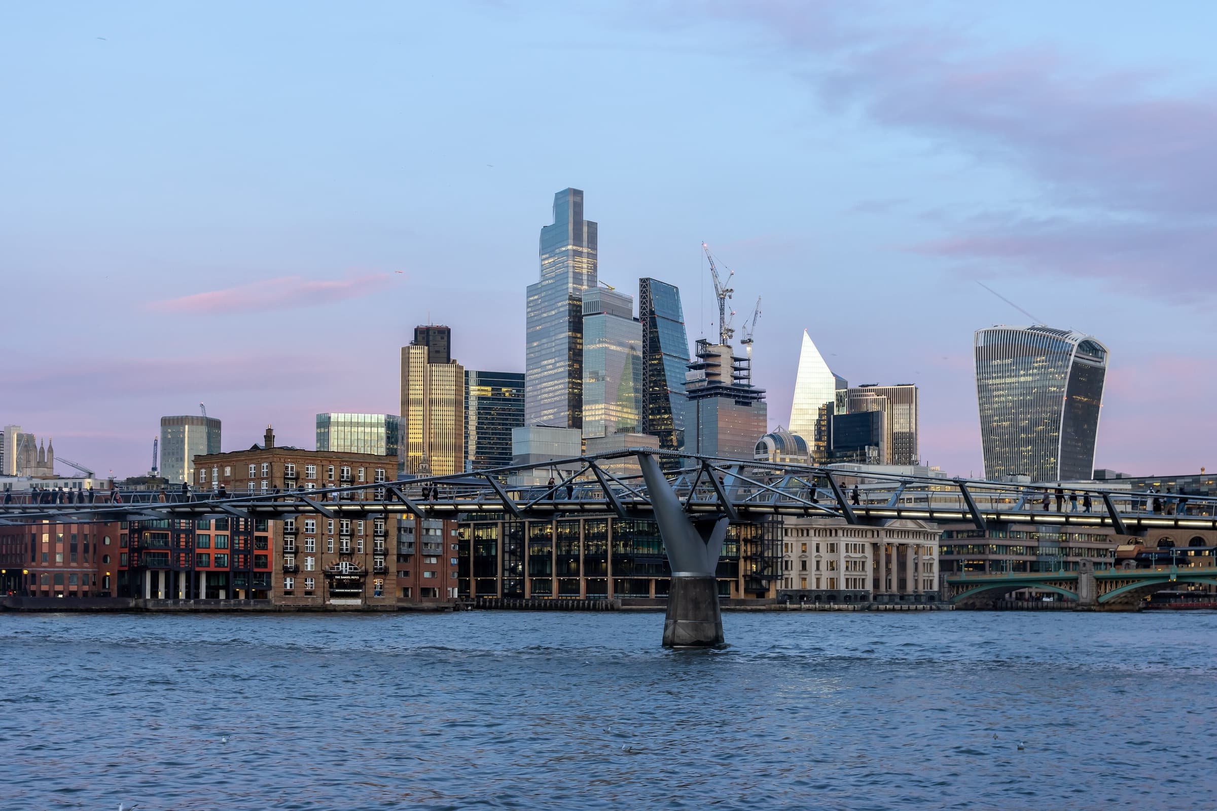 The City of London’s towers seen across the Thames and the Millennium Bridge
