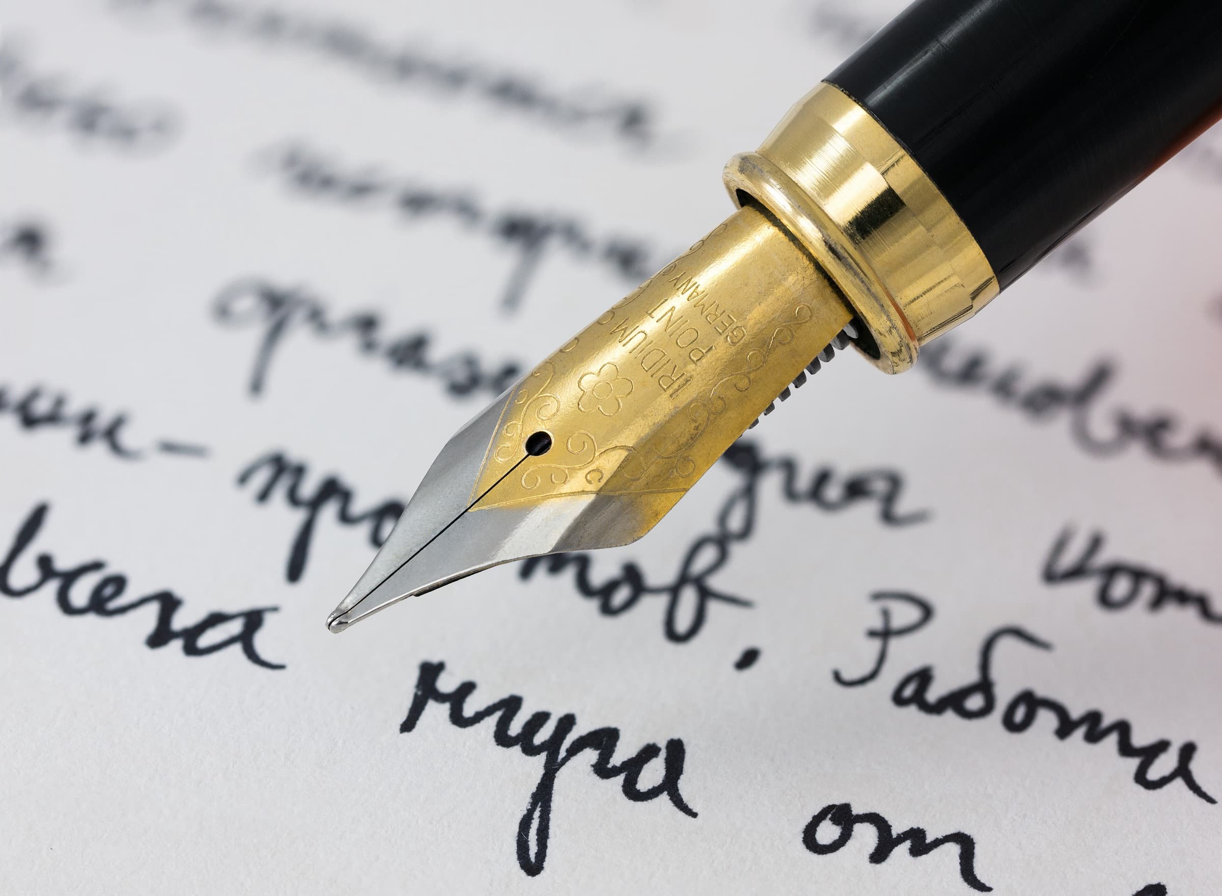 A gold-nibbed fountain pen writing on paper